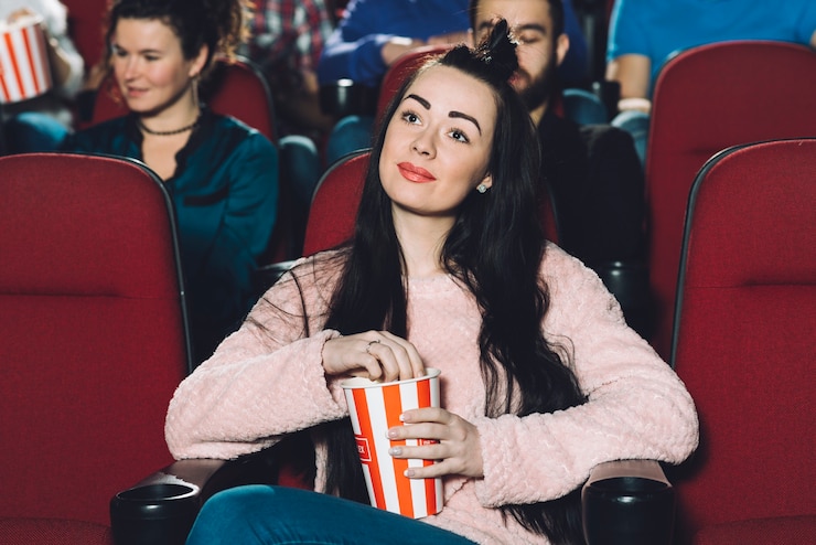 Charming brunette eating popcorn in cinema